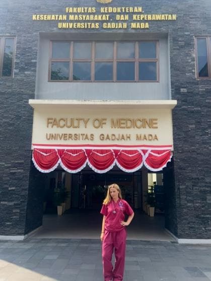 Cicely Green in maroon scrubs outside the Faculty of Medicine at Universitas Gadjah Mada, where she spent her elective
