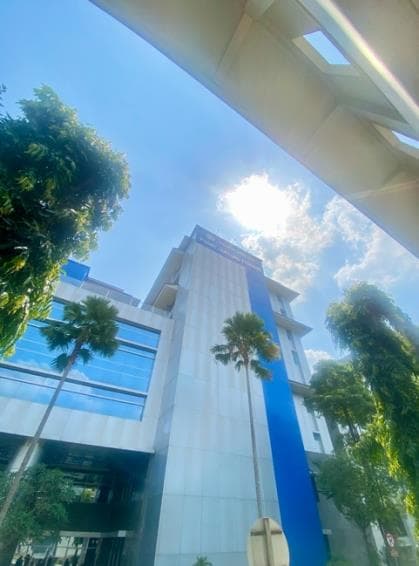 A modern building at Universitas Gadjah Mada, viewed from below among palm trees, where Cicely undertook her clinical placement